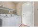 Functional laundry room with white appliances, shelving, and a door leading to the outdoors at 8606 W Caribbean Ln, Peoria, AZ 85381