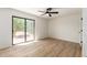 Bright bedroom featuring wood floors, neutral paint, a ceiling fan, and sliding glass door at 8913 W Country Club Trl, Peoria, AZ 85383
