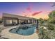 Inviting backyard pool and spa with rock waterfall, lush landscaping, and a covered patio area at 9576 W Blue Sky Dr, Peoria, AZ 85383