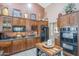 Close-up of the kitchen with wooden cabinets, granite countertops, and modern appliances including a black refrigerator at 9576 W Blue Sky Dr, Peoria, AZ 85383