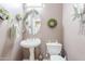 Charming powder room with a pedestal sink, decorative mirror, and stylish accents at 9576 W Blue Sky Dr, Peoria, AZ 85383