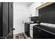 Well-organized laundry room featuring black appliances, white cabinets, and a modern design at 9721 E Juanita Ave, Mesa, AZ 85209