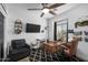Comfortable home office features a wooden desk, ceiling fan, gray accent chair, and lots of light at 9721 E Juanita Ave, Mesa, AZ 85209
