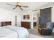 Comfortable main bedroom featuring a ceiling fan, dresser, and sliding barn door to the en suite bathroom at 9856 E Palladium Dr, Mesa, AZ 85212
