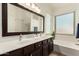 Bathroom with double sinks, framed mirror, white tub, and natural light at 1022 N Kirby St, Gilbert, AZ 85234