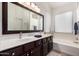 Well-lit bathroom featuring double sinks, dark wood cabinets, a large mirror, and a soaking tub at 1022 N Kirby St, Gilbert, AZ 85234