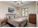 Cozy bedroom featuring a ceiling fan, a queen bed, and a wooden dresser with a landscape picture at 1022 N Kirby St, Gilbert, AZ 85234