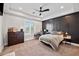Bedroom features a tray ceiling, black accent wall, window, ceiling fan, dresser and carpeted floors at 10448 E Glencove St, Mesa, AZ 85207
