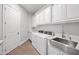 Bright laundry room with ample white cabinets, quartz counters, stainless steel sink, and washer/dryer hookups at 10448 E Glencove St, Mesa, AZ 85207