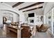 Bright living room featuring a stone fireplace, wooden beams, and comfortable brown leather furniture at 10448 E Glencove St, Mesa, AZ 85207