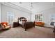 Spacious main bedroom with tray ceiling, two windows, ceiling fan, and sitting area with luxurious furniture at 10448 E Glencove St, Mesa, AZ 85207