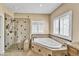 Bright bathroom features a glass enclosed shower, soaking tub and plantation shutters for natural light at 10997 E Altadena Ave, Scottsdale, AZ 85259