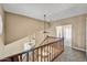 Bright hallway with a wooden staircase, decorative lighting, and neutral paint, leading to an open space at 10997 E Altadena Ave, Scottsdale, AZ 85259