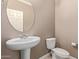 Half bathroom featuring a pedestal sink, toilet, and a round mirror at 11952 W Overlin Ln, Avondale, AZ 85323