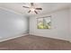 Bedroom with a ceiling fan, carpet flooring, and large window at 11952 W Overlin Ln, Avondale, AZ 85323