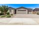 Tan home featuring a two-car garage, beautiful landscaping, and a brick driveway at 1268 E Jahns Dr, Casa Grande, AZ 85122