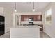 A bright, open kitchen features an island with a sink, wooden cabinets, and modern lighting fixtures at 1268 E Jahns Dr, Casa Grande, AZ 85122