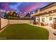 Expansive backyard with lush artificial turf, covered patio, and charming string lights at 1349 N Lakeshore Dr, Chandler, AZ 85226
