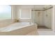 Bathroom showcasing the soaking tub, and shower with glass door and neutral tile at 1349 N Lakeshore Dr, Chandler, AZ 85226