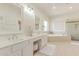 Bright bathroom with double sinks, soaking tub, glass shower, and neutral tile at 1349 N Lakeshore Dr, Chandler, AZ 85226