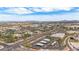 An aerial view showcasing an urban landscape with commercial buildings, roads, green spaces, and mountains in the distance at 16010 N 74Th Ln, Peoria, AZ 85382