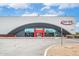 The building is characterized by a curved gray facade, large windows, and red accents, set against a bright sky at 16010 N 74Th Ln, Peoria, AZ 85382