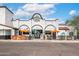 The building has a bright white facade, arched entryways, and colorful outdoor seating at 16010 N 74Th Ln, Peoria, AZ 85382