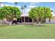 Spacious backyard boasting lush green grass, mature trees, and a covered patio perfect for outdoor gatherings at 17890 N 99Th Dr, Sun City, AZ 85373