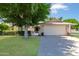Charming home featuring a lush lawn, mature tree, and a two-car garage with an American flag at 17890 N 99Th Dr, Sun City, AZ 85373