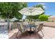 Outdoor patio seating area with a table, chairs, decorative umbrella, and a brick-paved surface at 17890 N 99Th Dr, Sun City, AZ 85373