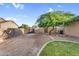 Spacious backyard with mature tree, rock landscaping, grass, and secure fencing, offering privacy and outdoor enjoyment at 18822 E Flintlock Dr, Queen Creek, AZ 85142
