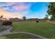 Expansive backyard with lush lawn, mature landscaping, and a block wall at sunset at 18822 E Flintlock Dr, Queen Creek, AZ 85142