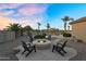 Cozy outdoor firepit with Adirondack chairs, palm trees, and backyard landscaping at 18822 E Flintlock Dr, Queen Creek, AZ 85142