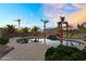 Backyard pool with waterfall feature surrounded by palm trees and lush landscaping at sunset at 18822 E Flintlock Dr, Queen Creek, AZ 85142