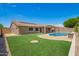Expansive backyard with a pool, patio, and well-maintained artificial grass at 20427 N 88Th Dr, Peoria, AZ 85382