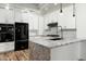 Modern kitchen with black appliances, light wood floors, and a spacious granite countertop island at 20802 N Grayhawk Dr # 1123, Scottsdale, AZ 85255