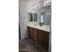 Bathroom with dual sinks with wood cabinets and large mirrors at 20941 N Leona Blvd, Maricopa, AZ 85138