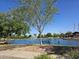 Picturesque lake with fountain, bench, and lush greenery under a clear blue sky at 20941 N Leona Blvd, Maricopa, AZ 85138