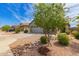 Desert landscaping frames this tan stucco home featuring a two-car garage and tiled roof at 343 S 202Nd Dr, Buckeye, AZ 85326