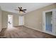 Spacious bedroom featuring neutral carpet, ceiling fan, and convenient access to the adjoining bathroom at 3800 S Cantabria Cir # 1077, Chandler, AZ 85248