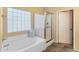 Bright bathroom featuring a soaking tub with glass-block window and separate glass-enclosed shower at 44574 W High Desert Trl, Maricopa, AZ 85139