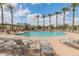 Community pool with lounge chairs, palm trees, and well-maintained landscaping at 44574 W High Desert Trl, Maricopa, AZ 85139