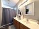 Bathroom featuring double sinks with wood cabinets and a framed mirrors, plus a shower curtain at 4601 W Fortune Dr, Anthem, AZ 85086