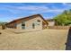 View of the home's beige stucco exterior and the gravel-covered backyard on a bright sunny day at 4723 W Samantha Way, Laveen, AZ 85339