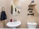 Charming powder room with a pedestal sink, round mirror, and decorative wall art at 5543 W Kowalsky Ln, Laveen, AZ 85339