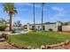 Expansive backyard showcases a pristine pool, well-manicured lawn, mature palm trees, and cozy seating area at 6401 E Voltaire Ave, Scottsdale, AZ 85254