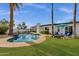 Lush backyard showcasing a sparkling pool, mature palm trees, green lawn, and cozy seating arrangements at 6401 E Voltaire Ave, Scottsdale, AZ 85254