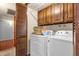 Bright laundry room has washer, dryer, wooden cabinets, and ample storage space to maximize organization at 6401 E Voltaire Ave, Scottsdale, AZ 85254