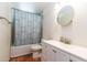 Fresh, clean bathroom with tiled shower, modern vanity, round mirror, and patterned shower curtain at 6501 W Columbus Ave, Phoenix, AZ 85033