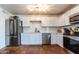 Bright kitchen featuring stainless steel appliances, white cabinetry, tile backsplash, and terra cotta tile flooring at 6501 W Columbus Ave, Phoenix, AZ 85033